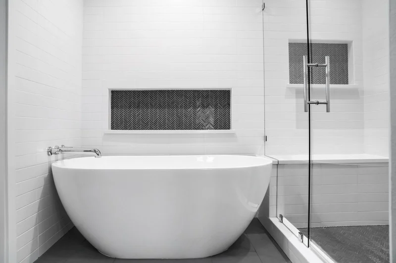Remodeled bathroom with a freestanding tub and herringbone tile niche