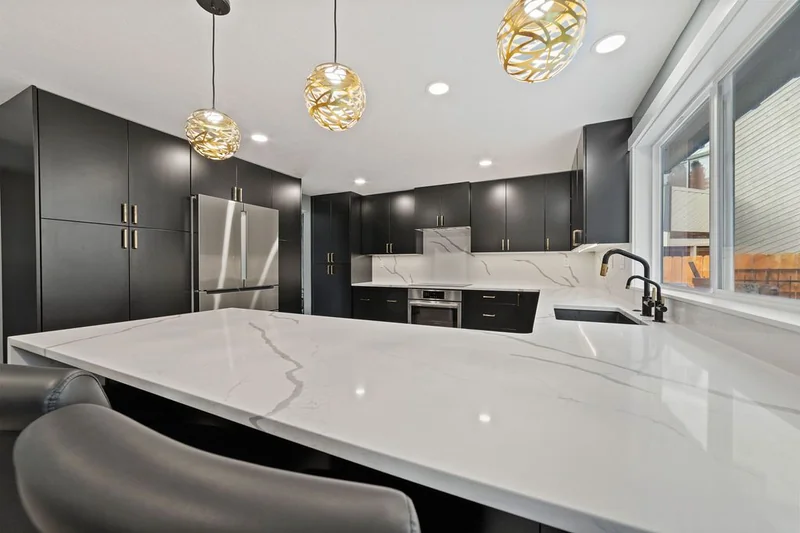 Quartz peninsula counter with gold pendants overhead